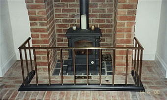 A fender fireguard with a Burnished Steel base, 5/8 ” uprights and convex top bar in antiqued brass. Low Level Fender in Burnished Steel with Solid Brass collars.